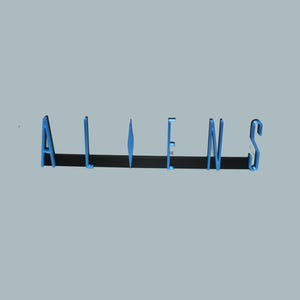 May include: The word "ALIENS" is displayed in a 3D blue font against a light gray background. The letters cast a dark shadow, enhancing the three-dimensional effect. The overall design is simple and modern.