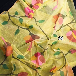 May include: A yellow sheer saree with a floral pattern in shades of pink, orange, and green. The saree has a delicate, almost translucent quality and features a subtle sheen. The fabric is lightweight and drapes beautifully.