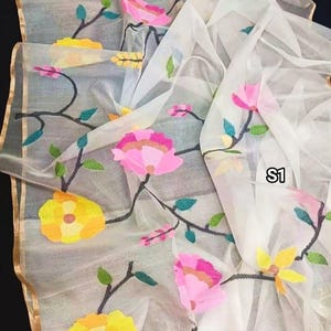 May include: White sheer fabric with embroidered floral designs in yellow, pink, and green. The fabric has a gold trim and the text "S1" is visible in the lower right corner.