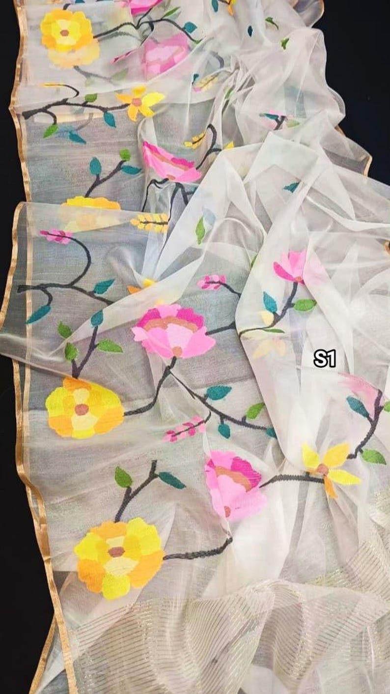 May include: White sheer fabric with embroidered floral designs in yellow, pink, and green. The fabric has a gold trim and the text "S1" is visible in the lower right corner.