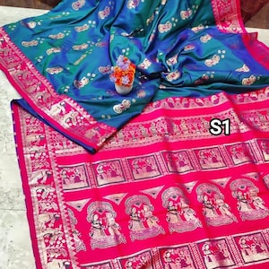 Könnte beinhalten: Ein traditioneller indischer Sari aus Seide in einem blauen und grünen Farbverlauf. Der Sari hat einen goldenen Rand mit aufwendigen Designs und einen rosafarbenen Pallu mit einem sich wiederholenden Muster aus goldenen Figuren.