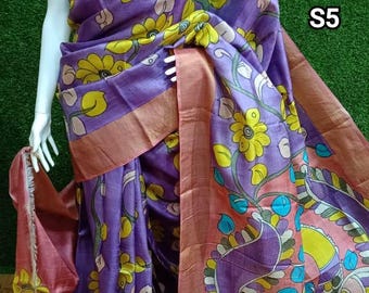 May include: A purple and pink silk saree with a floral and paisley print. The saree has a gold border and is draped on a mannequin. The saree is labeled "S5".