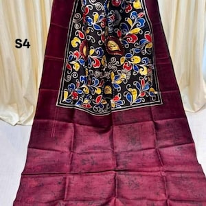 Puede incluir: Textil granate con un diseño floral negro y colorido. El textil presenta un panel central con fondo negro y un borde con un patrón floral repetido en rojo, amarillo y azul. El texto "S4" es visible.