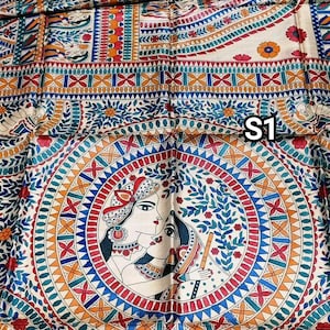 May include: A cream-coloured silk saree with a colourful hand-painted design. The design features a circular pattern with two figures in the centre, surrounded by floral motifs and geometric shapes. The saree also has a border with a similar design.