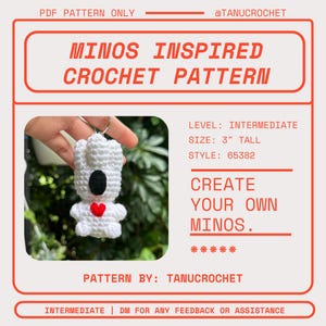 Op de afbeelding: Een wit gehaakt Minos-geïnspireerd patroon, ongeveer 7,6 cm hoog, met een zwart gezicht en een rood hart. Het patroon is van gemiddeld niveau en bevat de tekst "Create Your Own Minos."
