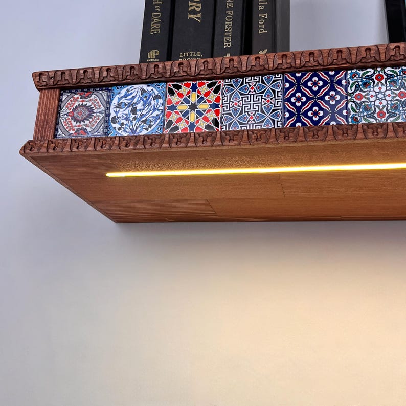 May include: A wooden wall shelf featuring a row of six decorative tiles with intricate blue, red, and white geometric and floral patterns. The shelf has a carved edge and an integrated horizontal LED light strip that emits a warm yellow glow.