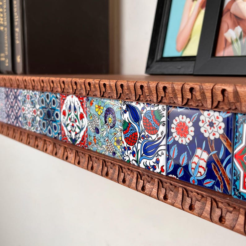 May include: A wooden shelf featuring a carved, scalloped edge and a row of square ceramic tiles. The tiles display intricate, colorful floral and geometric patterns in shades of blue, red, green, and white, arranged in a continuous horizontal line.