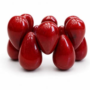 May include: A bracelet composed of multiple smooth, glossy, deep red, teardrop-shaped beads arranged in a circular formation. Each bead features a polished finish that reflects light, creating a uniform and vibrant appearance throughout the piece.