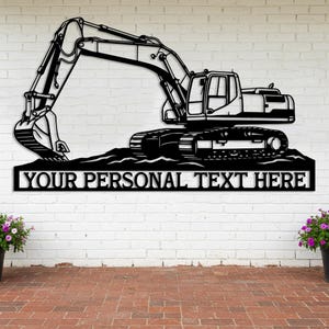 May include: Black metal excavator wall art. The excavator is depicted in a side profile, with the text "YOUR PERSONAL TEXT HERE" below. The excavator is set against a white brick wall and a red brick patio.