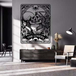 May include: A black and white wall art piece featuring a tarot card design titled THE LOVERS. The illustration depicts two skeletons facing each other in a romantic pose, surrounded by intricate floral patterns, roses, and a sun symbol above.
