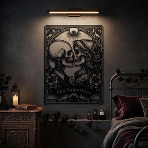 May include: A black metal wall art piece featuring a cutout design of two skeletons facing each other in a romantic pose, surrounded by roses and ornate filigree. The text The Valentines is centered at the bottom below the two figures.