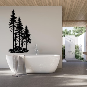May include: A white bathtub with a gray towel draped over the side, set against a white wall with a black silhouette of three pine trees on a rocky landscape.