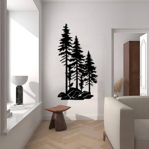 May include: Black silhouette wall art featuring three pine trees with a bird perched on a rock. The trees are set against a white background and are surrounded by rocks.