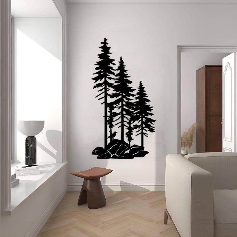 May include: Black silhouette wall art featuring three pine trees with a bird perched on a rock. The trees are set against a white background and are surrounded by rocks.