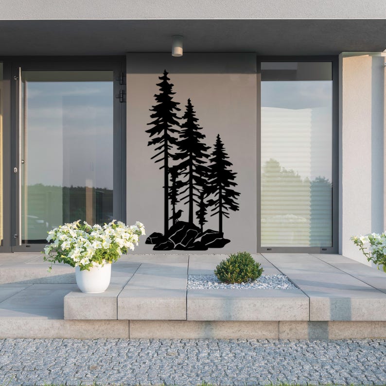 May include: Black silhouette of three pine trees on a gray wall. The trees are in a row, with the tallest tree in the center. The trees are set against a backdrop of a modern home with a patio.