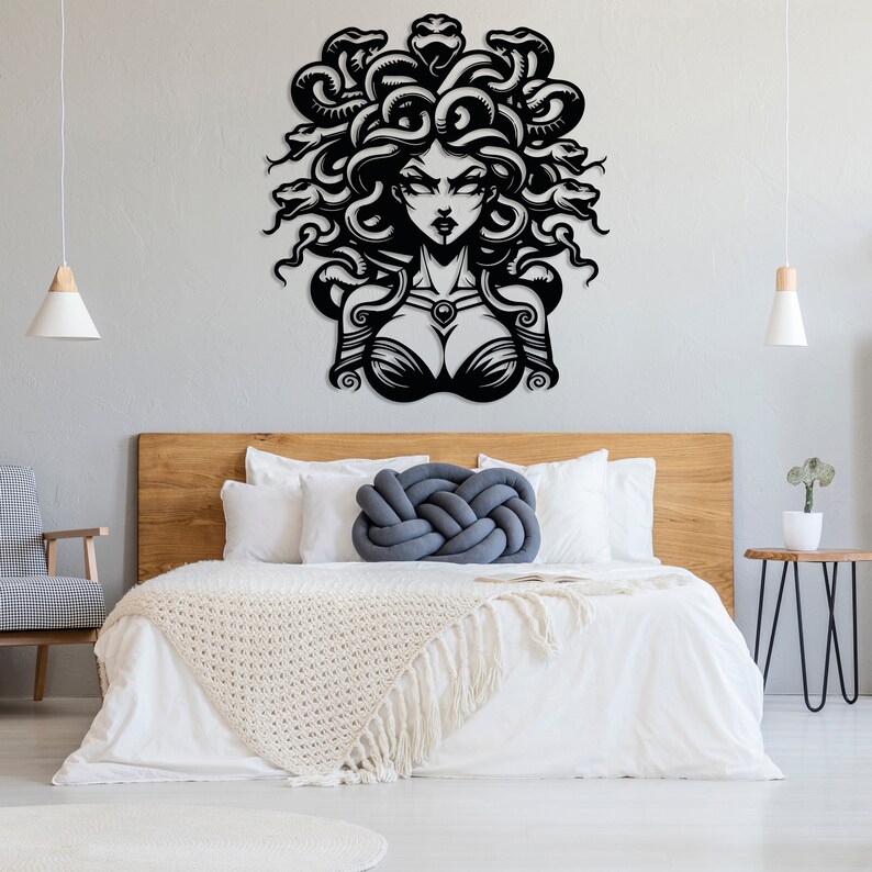 May include: Black and white metal wall art depicting Medusa, a mythical Greek figure with snakes for hair. The art is mounted on a white wall above a wooden headboard and white bedding.