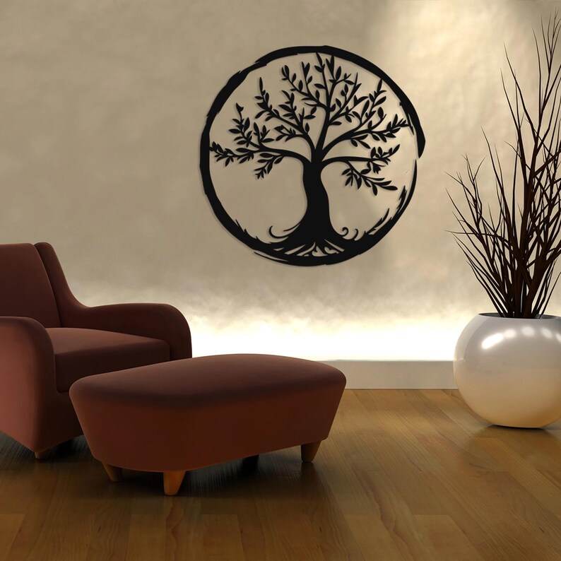 Peut inclure: Une sculpture murale en m&eacute;tal noir repr&eacute;sentant un arbre de vie avec des branches et des racines complexes, sur un mur beige. Un fauteuil et un pouf marron sont au premier plan, et une plante en pot se trouve &agrave; droite de l'image.