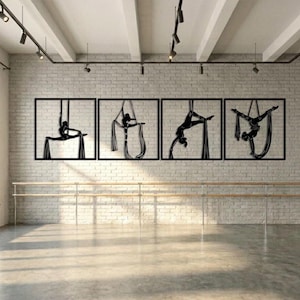 Op de afbeelding: Een set van vier wandkunstwerken van zwart metaal, elk in een vierkant frame, met silhouetten van personen die aerial silk-poses uitvoeren. De figuren zijn in verschillende posities hangend aan stoffen doeken afgebeeld.