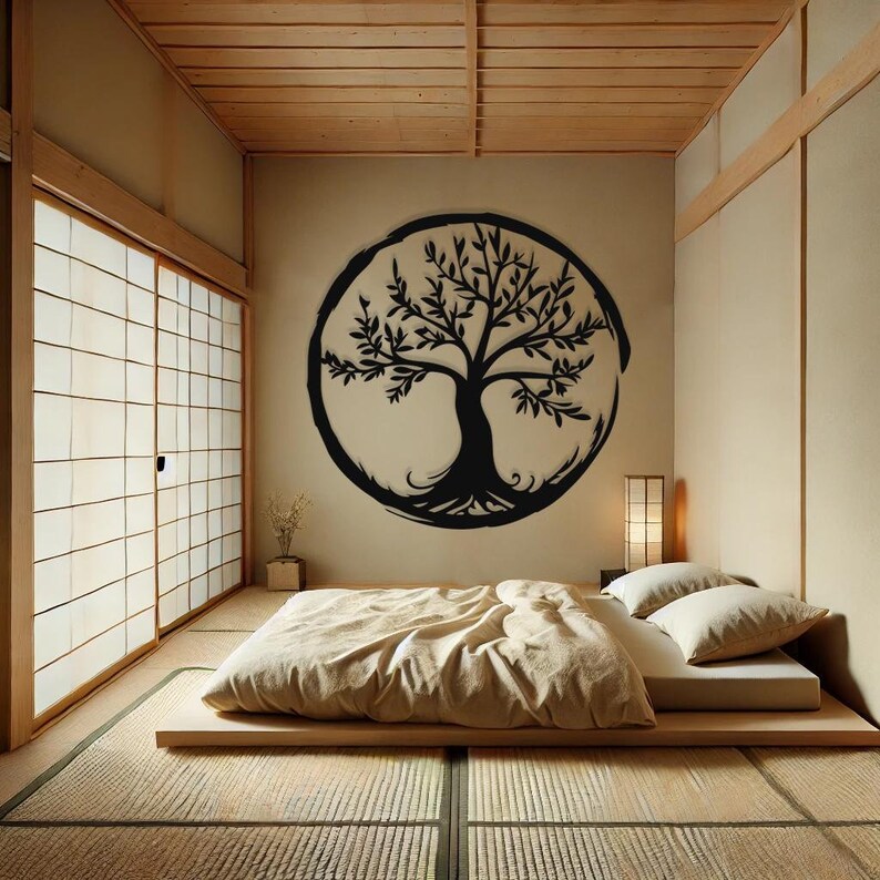 Peut inclure: Un autocollant mural en forme d'arbre de vie noir et blanc dans un cercle sur un mur beige. L'autocollant est au-dessus d'un lit futon avec une couette beige et deux oreillers blancs. La pi&egrave;ce a un plafond en bois et une porte coulissante avec un cadre en bois.
