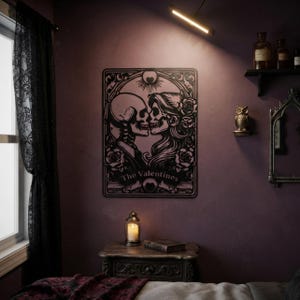 May include: A black metal wall art piece featuring a rectangular frame with an intricate design of two skeletons facing each other, surrounded by roses and a sun motif. The text "The Valentines" is printed at the bottom of the central illustration.