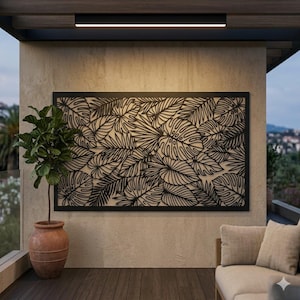 May include: A black metal wall art panel with a detailed leaf pattern. The rectangular artwork is mounted on a beige wall. A potted plant and outdoor seating are also visible.