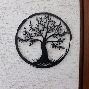 Peut inclure: D&eacute;coration murale en m&eacute;tal noir en forme d'arbre de vie avec un design circulaire. L'arbre a des branches et des racines complexes.