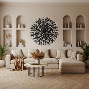Puede incluir: Una escultura de pared de metal negro en forma de un gran &aacute;rbol circular ramificado. La escultura est&aacute; colgada en una pared beige en un sal&oacute;n con un sof&aacute; seccional beige y una mesa de caf&eacute;.