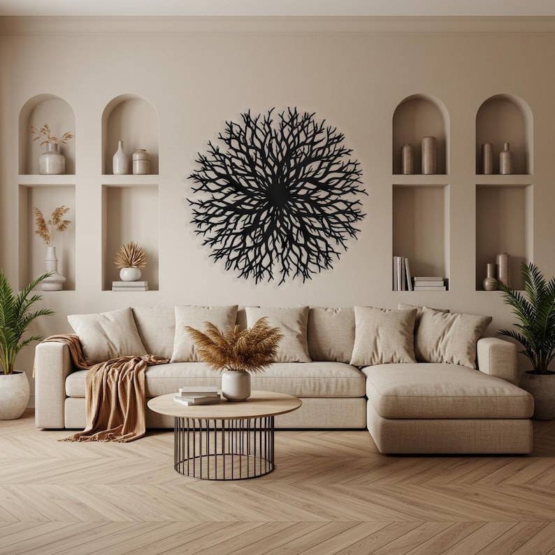 Puede incluir: Una escultura de pared de metal negro en forma de un gran &aacute;rbol circular ramificado. La escultura est&aacute; colgada en una pared beige en un sal&oacute;n con un sof&aacute; seccional beige y una mesa de caf&eacute;.