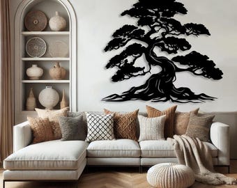 Puede incluir: Una silueta negra de metal de un bonsái montada en una pared blanca en una sala de estar. El árbol está en el centro de la imagen y está rodeado por un sofá blanco con almohadas marrones y un puf de punto marrón.
