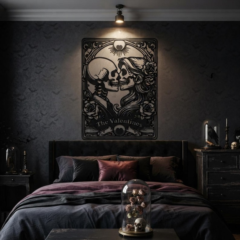 May include: A black metal wall art piece featuring a stylized illustration of two skulls facing each other, surrounded by roses and decorative filigree. The text "The Valentines" is printed at the bottom of the rectangular frame.