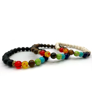 May include: Three beaded bracelets with a variety of colorful stones. One bracelet features black lava beads, another has brown and gold beads, and the third is white with a textured pattern. Each bracelet has a rainbow of colored beads.