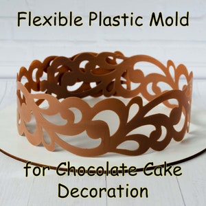 Puede incluir: Un molde de plástico marrón para decorar tartas de chocolate. El molde tiene un diseño decorativo e intrincado.