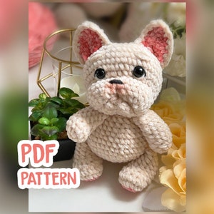 Może przedstawiać: Wzór na szydełku na pluszową zabawkę amigurumi francuskiego buldoga. Wzór jest dostępny jako plik PDF do pobrania. Zabawka jest kremowa z różowymi uszami i czarnymi oczami.