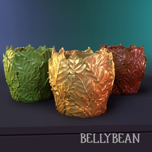 May include: Three decorative leaf-shaped planters in green, gold, and brown. The planters are made of a smooth, textured material and have a unique, organic design.