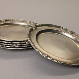Puede incluir: Un conjunto de fuentes ovaladas plateadas con bordes festoneados ornamentados. Una fuente est&aacute; separada, mostrando los detalles del dise&ntilde;o. Las fuentes tienen una superficie reflectante, lo que sugiere un material met&aacute;lico.