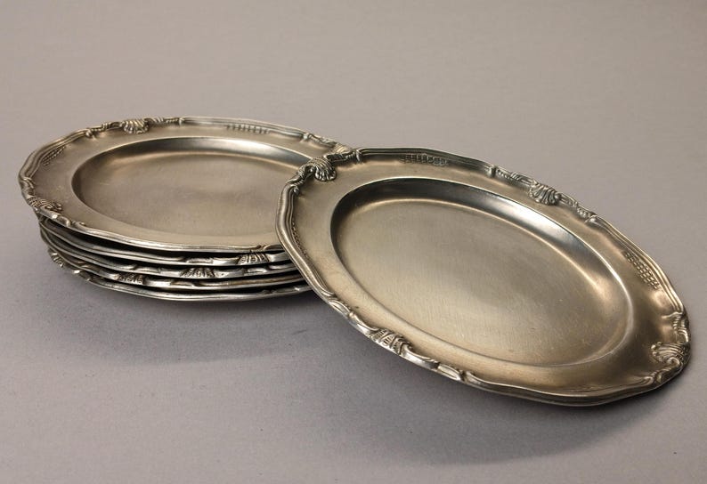 Puede incluir: Un conjunto de fuentes ovaladas plateadas con bordes festoneados ornamentados. Una fuente est&aacute; separada, mostrando los detalles del dise&ntilde;o. Las fuentes tienen una superficie reflectante, lo que sugiere un material met&aacute;lico.