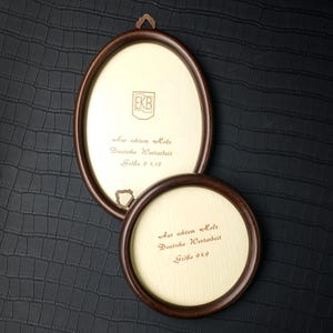 Könnte beinhalten: Zwei ovale und runde Bilderrahmen aus Holz mit dunkelbraunen Rahmen. Der ovale Rahmen ist 22,86 x 33,02 cm groß, und der runde Rahmen ist 22,86 x 22,86 cm groß. Die Rahmen haben einen hellbeige Innenraum mit deutschem Text.