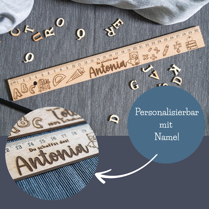 May include: A wooden ruler with a personalized name, "Antonia", engraved on it. The ruler features a colorful design with letters, numbers, and illustrations of school supplies. The text "Du schaffst das!" (You can do it!) is also engraved on the ruler.