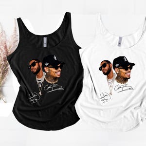 May include: A black tank top and a white tank top, each featuring a graphic print of two portraits of a man wearing sunglasses and a baseball cap, layered with multiple silver chain necklaces and a signature script text below the images.