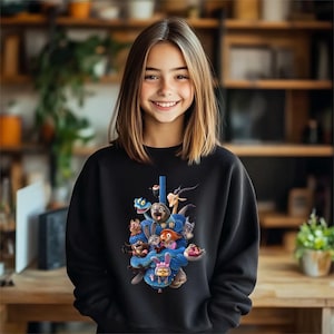 May include: Black sweatshirt featuring a colorful graphic of animated animal characters. The design includes a blue snake wrapped around the characters. The sweatshirt is worn by a person with long brown hair.