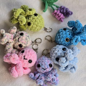 May include: A set of ten crocheted octopus keychains in various colours, including pink, blue, green, and white. Each octopus has large, round eyes and a textured, yarn-like body.