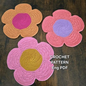 May include: Three handmade crochet flower coasters in shades of pink, orange, and yellow. Each coaster has a contrasting center. The text "CROCHET PATTERN Eng PDF" is visible in the image.