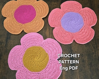 May include: Three handmade crochet flower coasters in shades of pink, orange, and yellow. Each coaster has a contrasting center. The text "CROCHET PATTERN Eng PDF" is visible in the image.