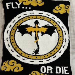 May include: Black and gold crochet blanket featuring a dragon design in the centre. The blanket has the words "FLY... OR DIE" at the top and bottom.