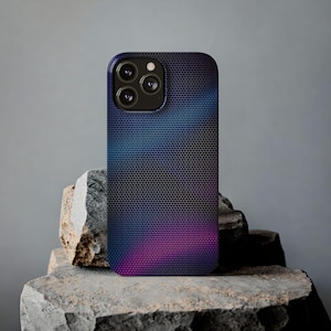 May include: A smartphone case with a gradient design in shades of blue and purple. The case has a textured, honeycomb-like pattern and a black camera module. The phone case is displayed on a rough, gray stone surface.