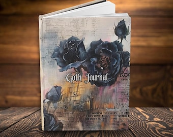 May include: A hardcover journal with a cream-colored background featuring dark blue and black rose illustrations, layered with faint script text and abstract brown and orange paint strokes. The text Goth Journal is printed in a stylized font.
