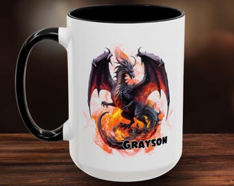 May include: A white ceramic mug with a black handle and interior rim. The front features a graphic of a black dragon with red-tipped wings surrounded by orange and yellow flames. The name GRAYSON is printed in black capital letters below the dragon.