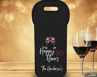 May include: Black wine bottle tote bag with a handle, featuring a design with two wine glasses clinking, the words "Happy 50 Years" and "The Henderson's" in white and red. Two wine glasses filled with red wine are in the foreground.