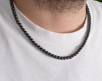 May include: A black beaded necklace with a simple design. The necklace is made of small, round beads and is worn by a person.