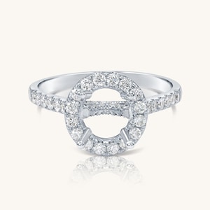 Könnte beinhalten: Ein silberner Ring-Sockel mit einem runden Halo aus kleinen Diamanten und einer Pavé-Diamanten-Band.